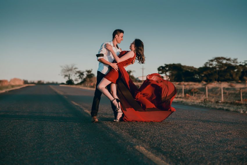 man and woman doing dance post in concrete road at daytime